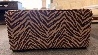 A modern square cube ottoman upholstered in a textured brown and beige zebra-stripe woven fabric in good condition.
