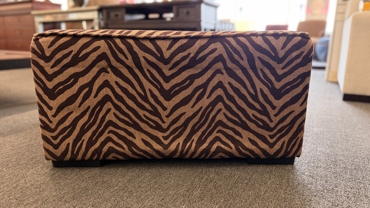 A modern square cube ottoman upholstered in a textured brown and beige zebra-stripe woven fabric in good condition.