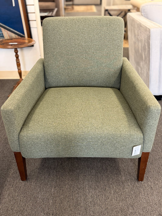 A modern transitional accent armchair upholstered in textured sage green woven fabric with track arms and tapered dark wood legs in good condition.