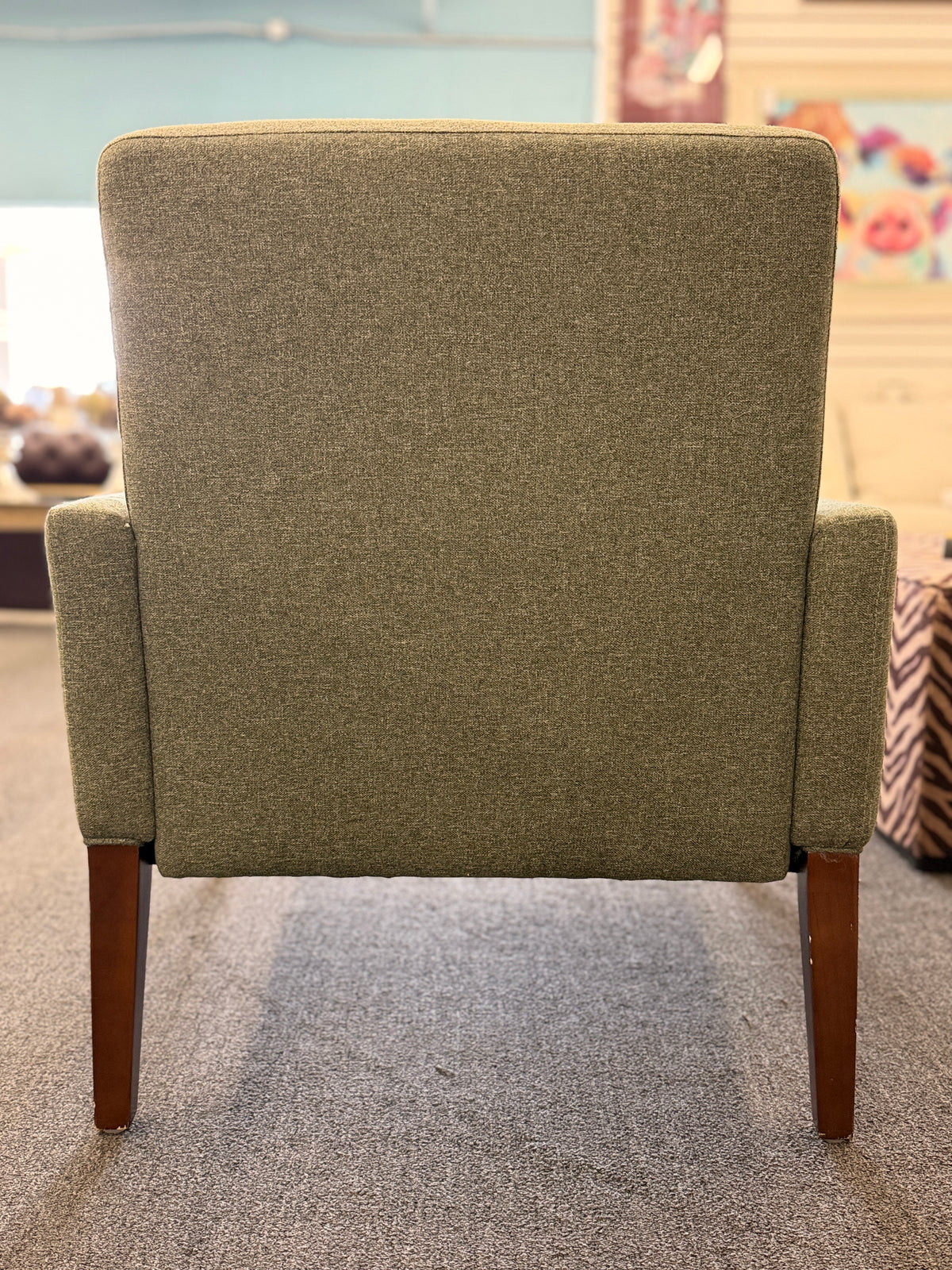 A modern transitional accent armchair upholstered in textured sage green woven fabric with track arms and tapered dark wood legs in good condition.