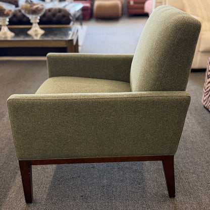 A modern transitional accent armchair upholstered in textured sage green woven fabric with track arms and tapered dark wood legs in good condition.