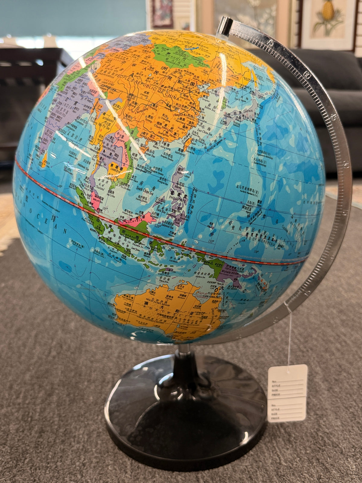 A modern world globe mounted on a brushed metal semi-meridian arc with a glossy black circular pedestal base in excellent condition.