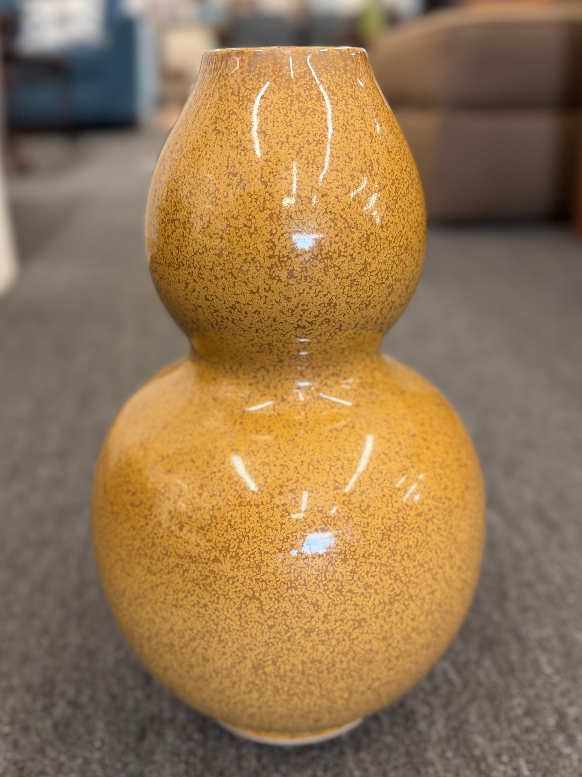 A double-gourd shaped ceramic vase in a mustard-yellow hue featuring a glossy speckled glaze finish.