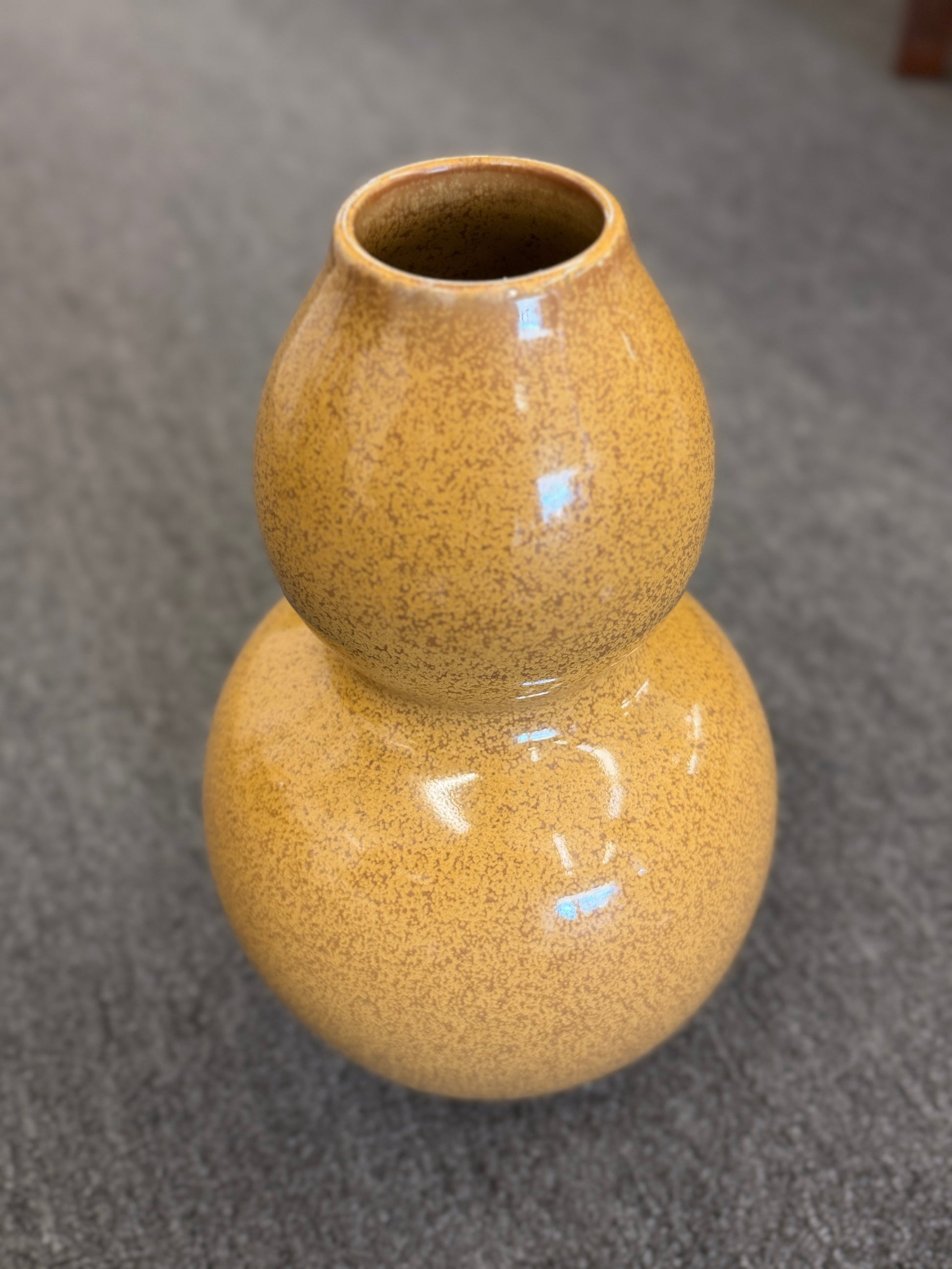 A double-gourd shaped ceramic vase in a mustard-yellow hue featuring a glossy speckled glaze finish.