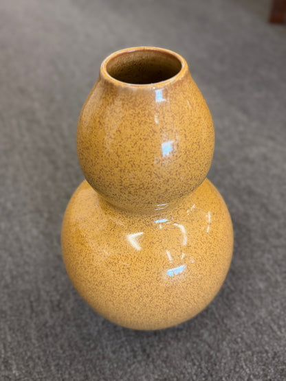 A double-gourd shaped ceramic vase in a mustard-yellow hue featuring a glossy speckled glaze finish.