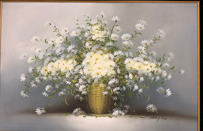 A traditional still-life canvas painting by Nancy Lee showing a dense bouquet of white daisies in a wicker basket, set in a dark velvet liner and an ornate gilded gold frame.