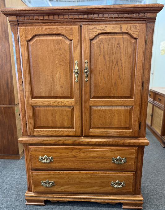 Traditional oak wood armoire and wardrobe chest featuring two doors and two lower drawers at 2nd Debut Houston consignment showroom