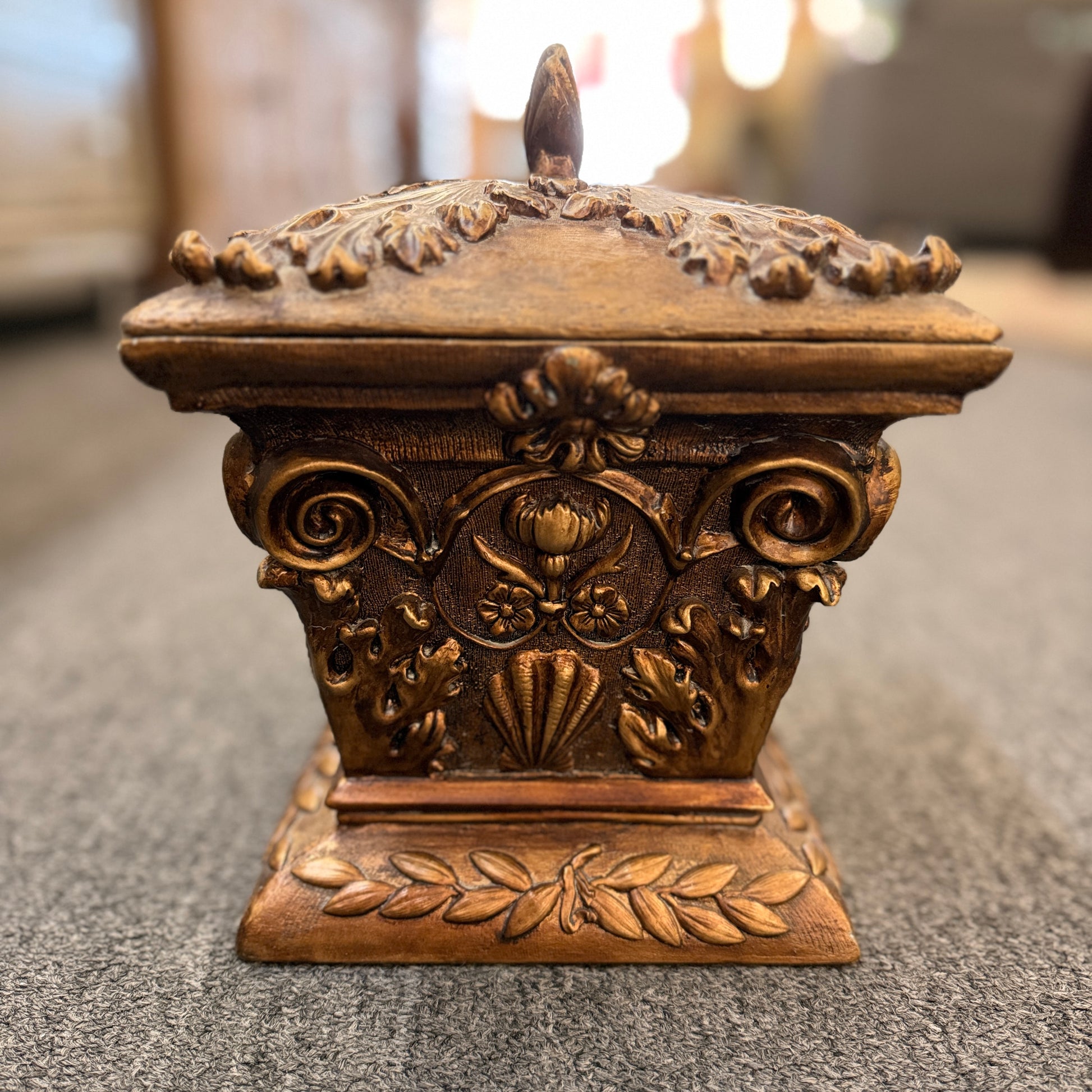 An ornate antique-style ceramic decorative box with a lid, featuring classical floral relief motifs and a distressed gold finish.