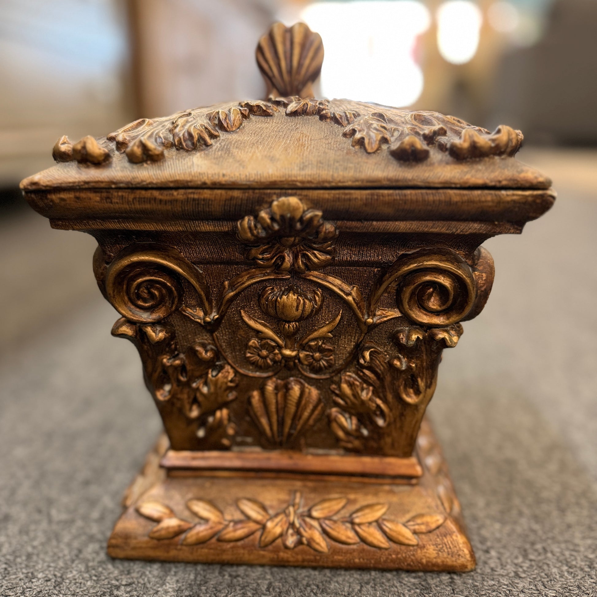 An ornate antique-style ceramic decorative box with a lid, featuring classical floral relief motifs and a distressed gold finish.