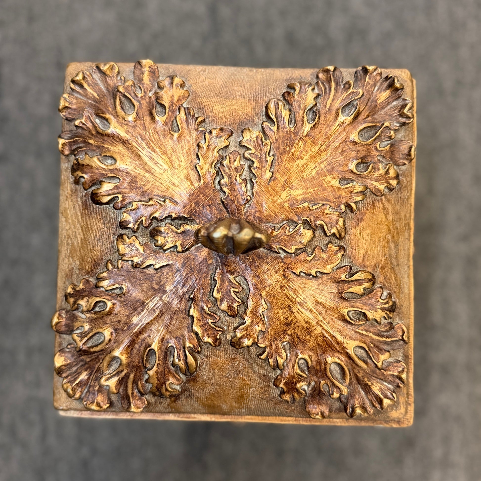 An ornate antique-style ceramic decorative box with a lid, featuring classical floral relief motifs and a distressed gold finish.