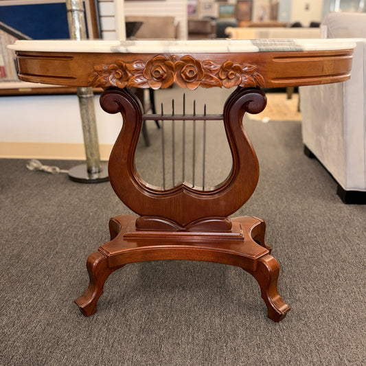 An ornate accent table featuring a white marble top, carved floral apron details, and a traditional lyre-shaped wooden base in excellent condition.