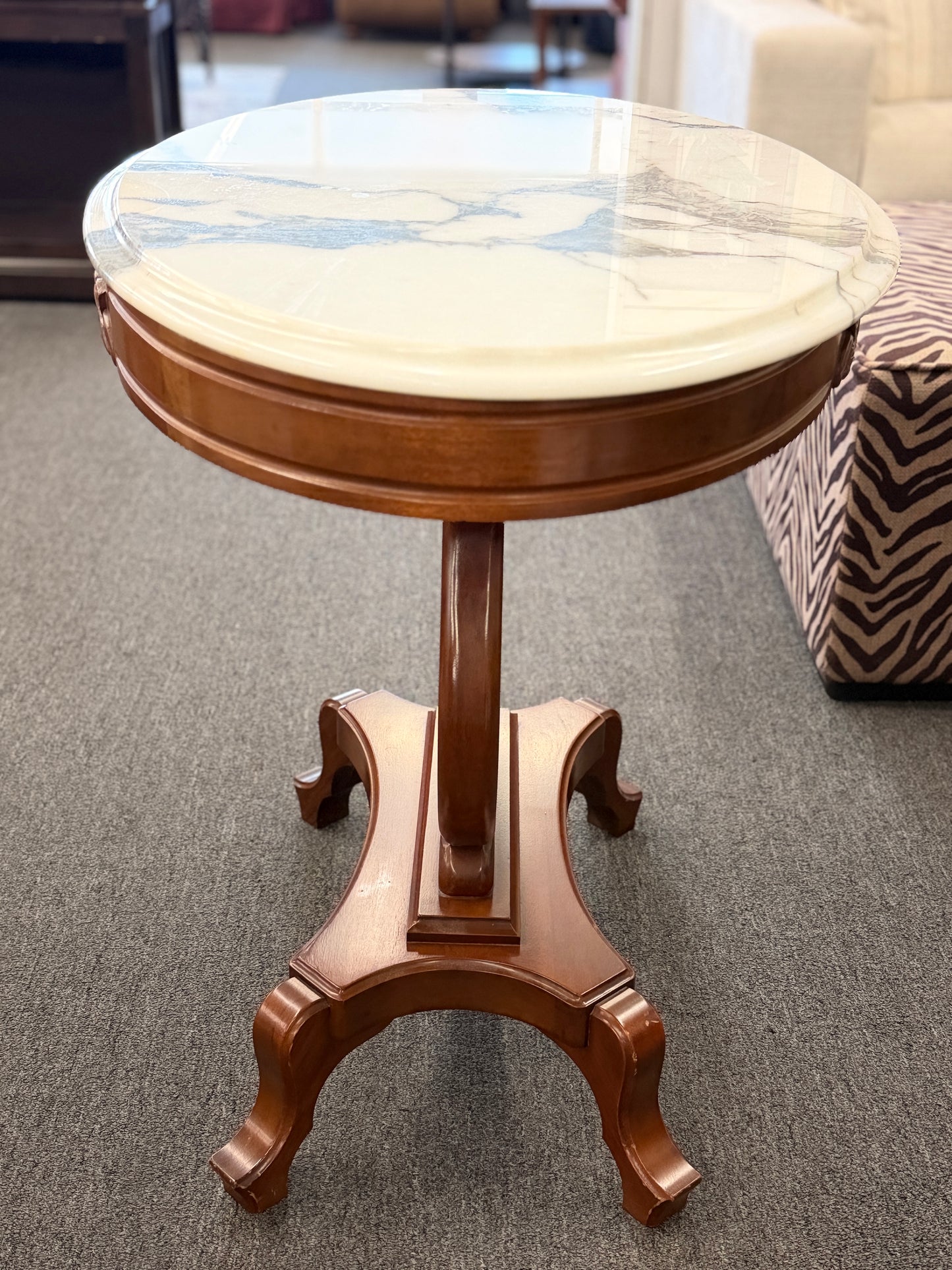 An ornate accent table featuring a white marble top, carved floral apron details, and a traditional lyre-shaped wooden base in excellent condition.