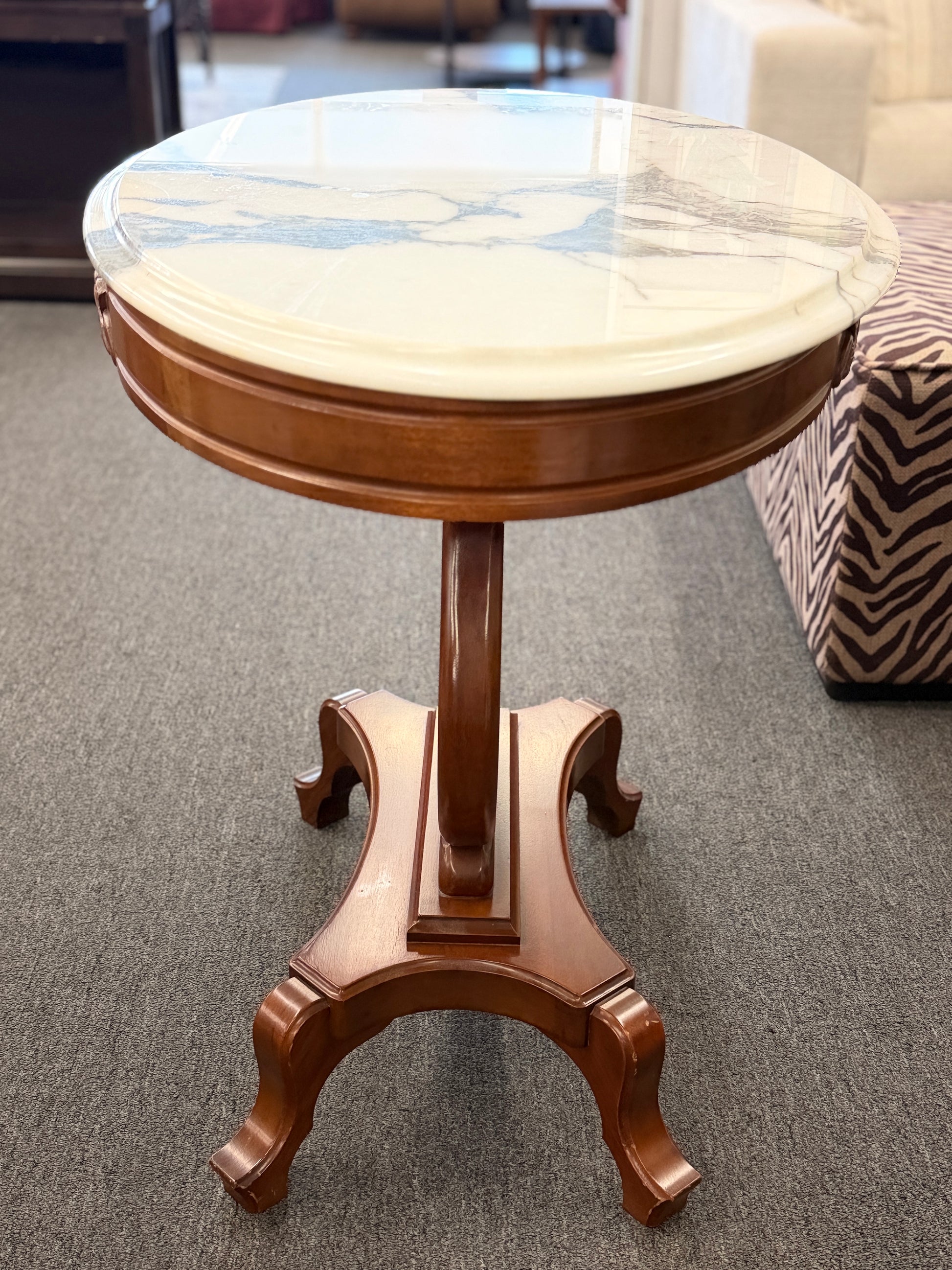 An ornate accent table featuring a white marble top, carved floral apron details, and a traditional lyre-shaped wooden base in excellent condition.