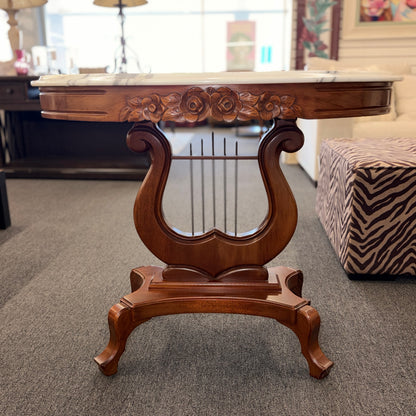 An ornate accent table featuring a white marble top, carved floral apron details, and a traditional lyre-shaped wooden base in excellent condition.