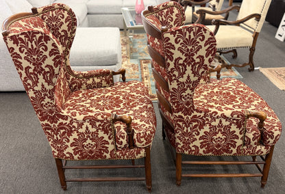 Pair of classic wingback armchairs upholstered in a bold burgundy and cream damask floral pattern detailed with nailhead trim and carved wooden legs in good condition.
