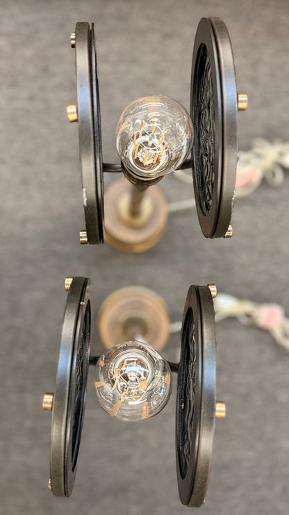Pair of industrial-style tall table or buffet lamps featuring antiqued bronze and brass metal stems, ribbed bases, and round porthole or spotlight heads with textured glass lenses in excellent condition.