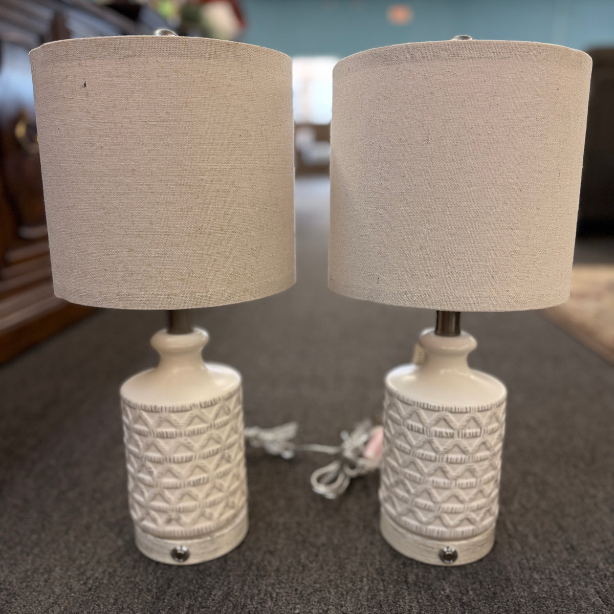A pair of modern ceramic table lamps featuring textured geometric cream bases and neutral linen drum shades in excellent condition.