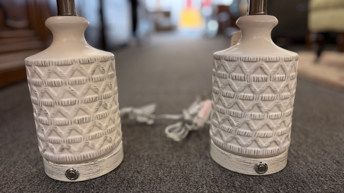A pair of modern ceramic table lamps featuring textured geometric cream bases and neutral linen drum shades in excellent condition.
