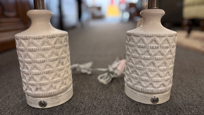 A pair of modern ceramic table lamps featuring textured geometric cream bases and neutral linen drum shades in excellent condition.