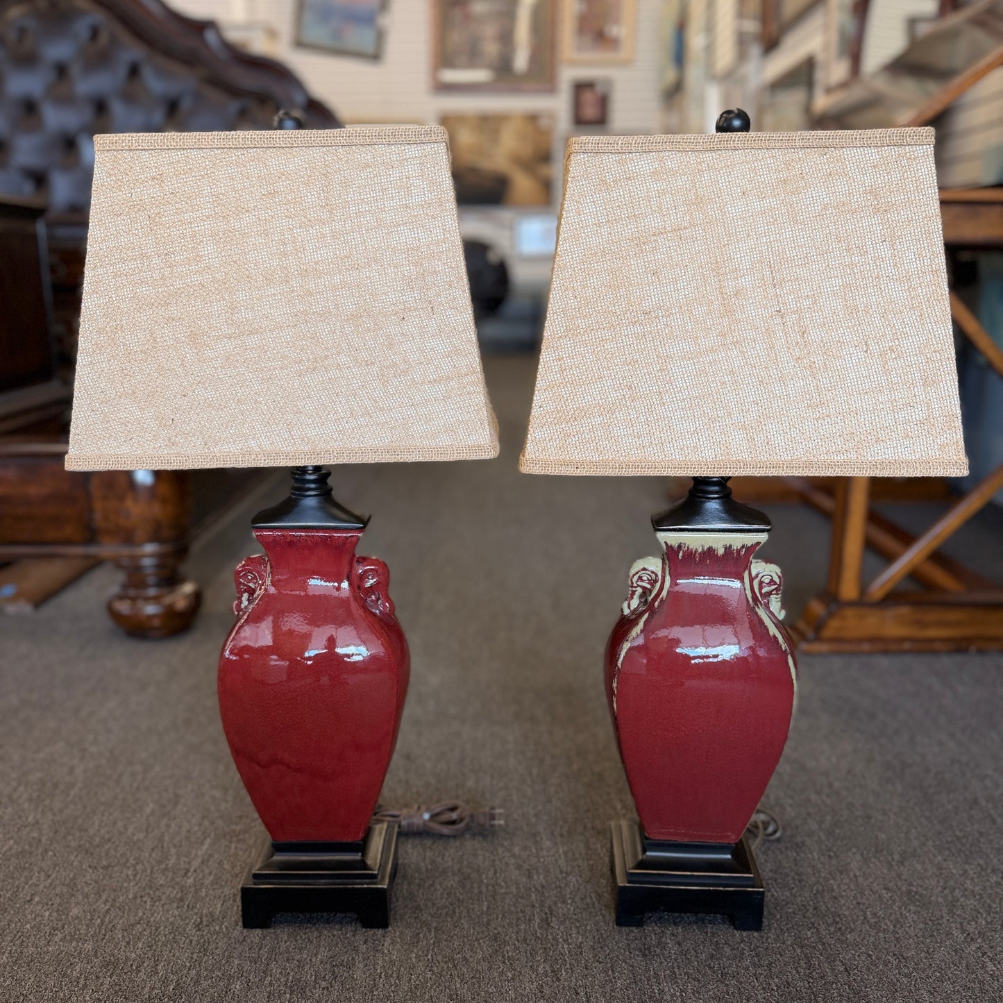 A matching pair of modern table lamps featuring ceramic bodies, wood bases, and fabric shades in excellent condition.