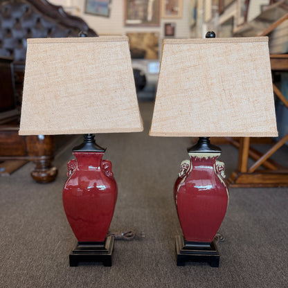 A matching pair of modern table lamps featuring ceramic bodies, wood bases, and fabric shades in excellent condition.