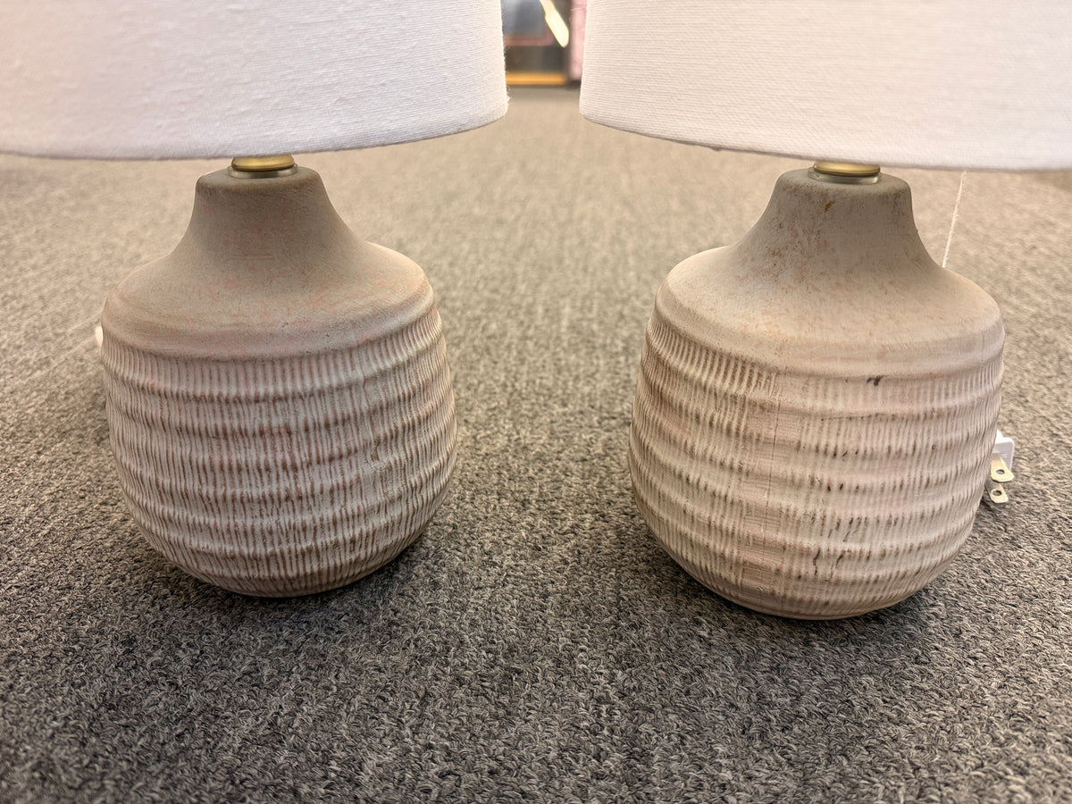 A pair of matching table lamps featuring rounded textured ceramic bases and simple white drum shades in excellent condition.