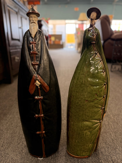 Two tall stylized ceramic figurines of standing figures, one finished in a dark glaze and the other in green in excellent condition.