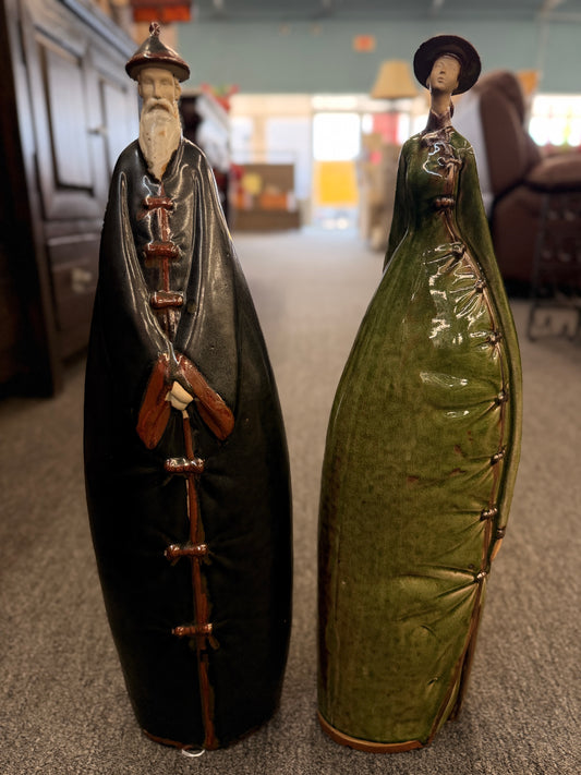 Two tall stylized ceramic figurines of standing figures, one finished in a dark glaze and the other in green in excellent condition.