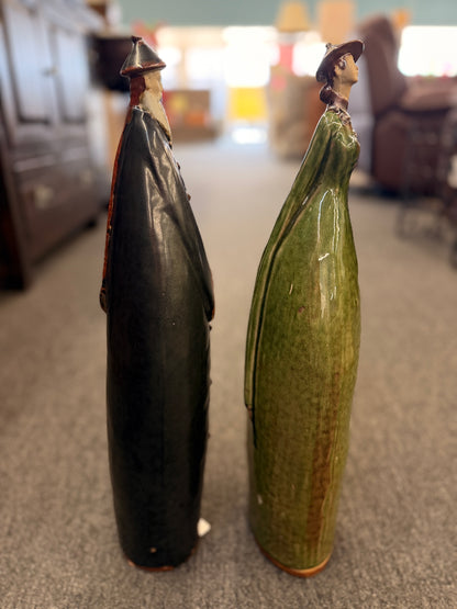 Two tall stylized ceramic figurines of standing figures, one finished in a dark glaze and the other in green in excellent condition.