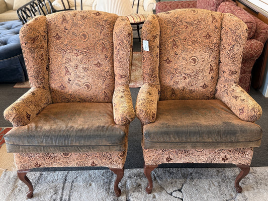 Pair of traditional wingback accent chairs upholstered in tan and brown paisley fabric with curved Queen Anne-style wooden legs.