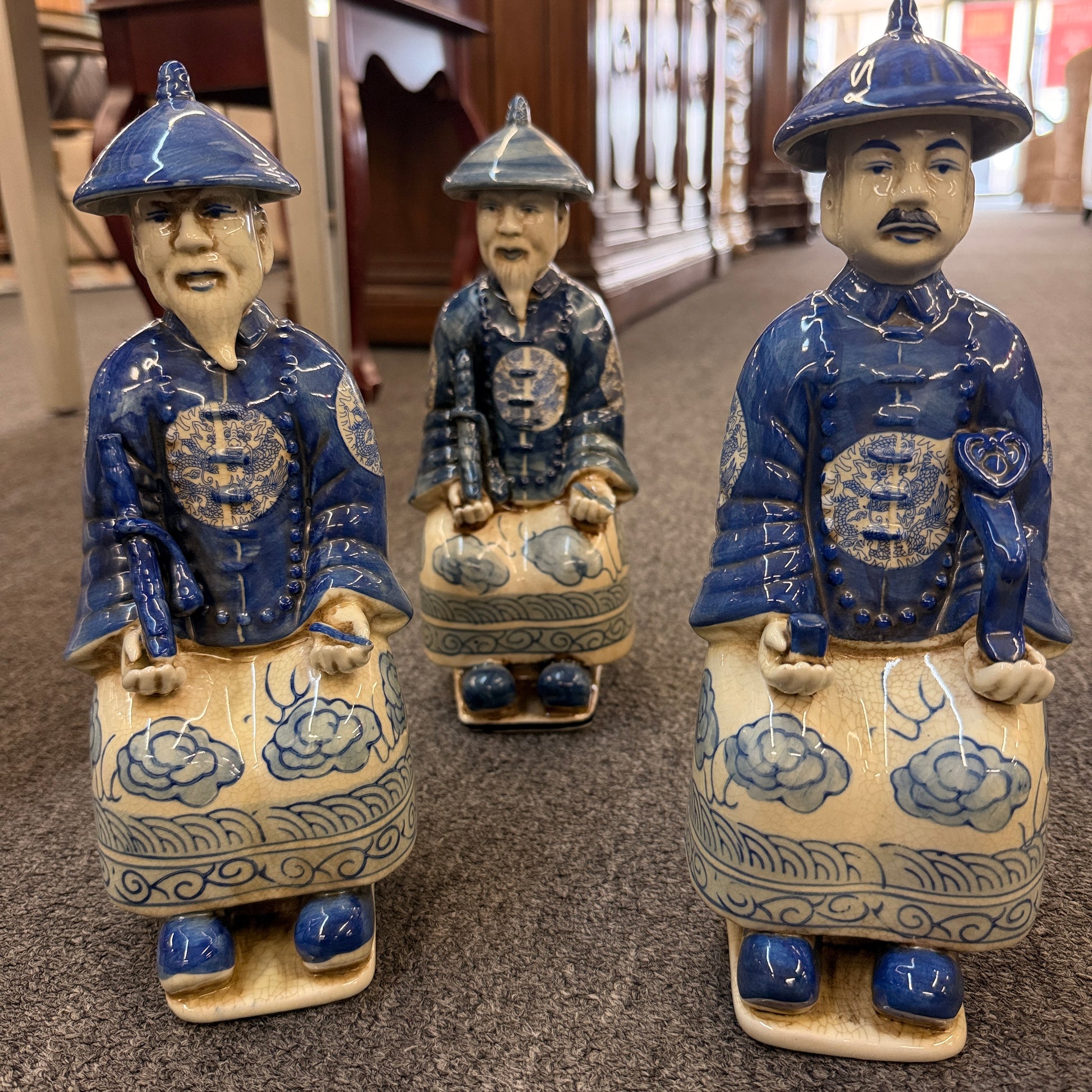 A set of six hand-painted blue and white porcelain figurines depicting seated Qing Dynasty scholars in traditional robes and mandarin hats in excellent condition.