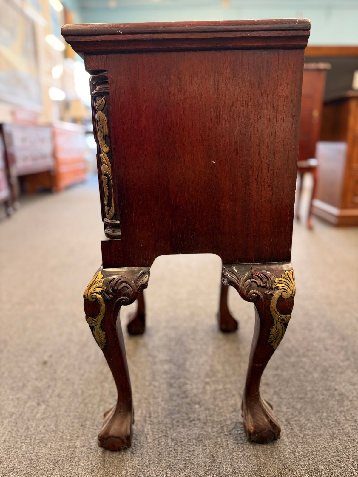 A Queen Anne-style two-drawer nightstand in rich mahogany featuring ornate brass hardware, cabriole legs, and ball-and-claw feet in good condition.