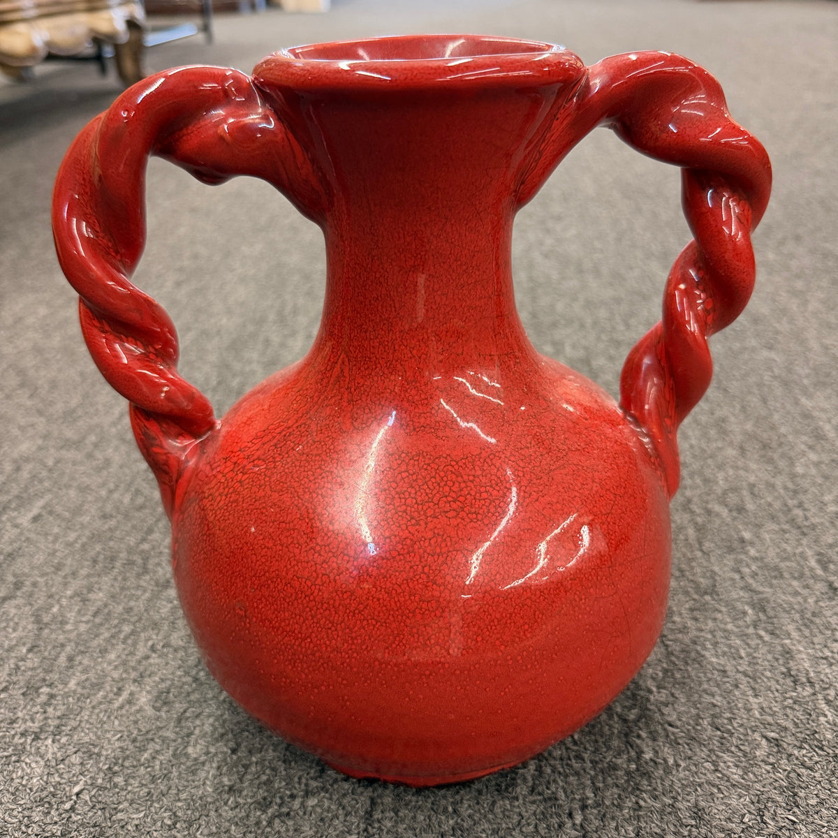 A red crackle-glazed ceramic urn vase featuring two twisted rope handles and a bulbous body in excellent condition.
