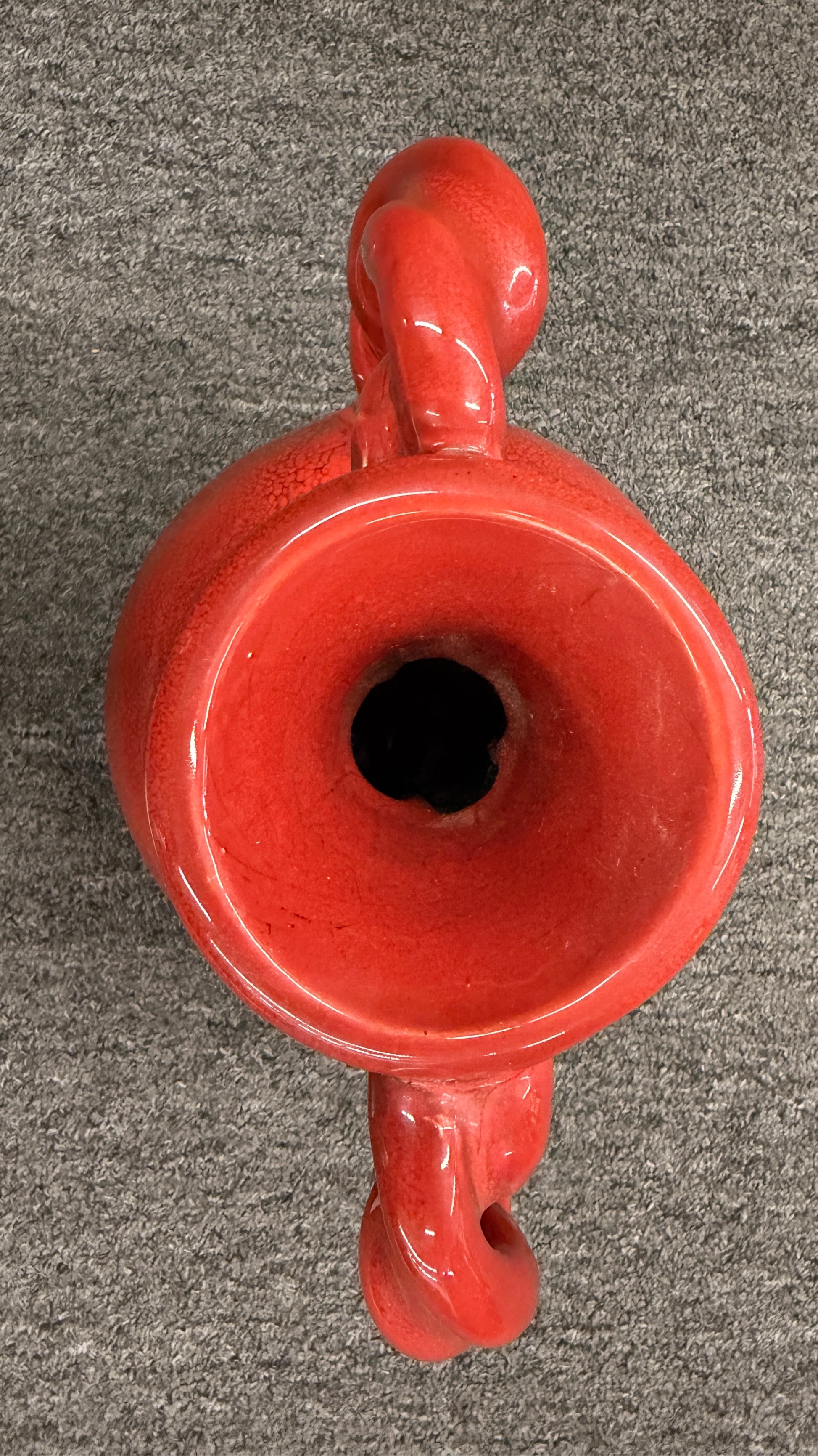 A red crackle-glazed ceramic urn vase featuring two twisted rope handles and a bulbous body in excellent condition.