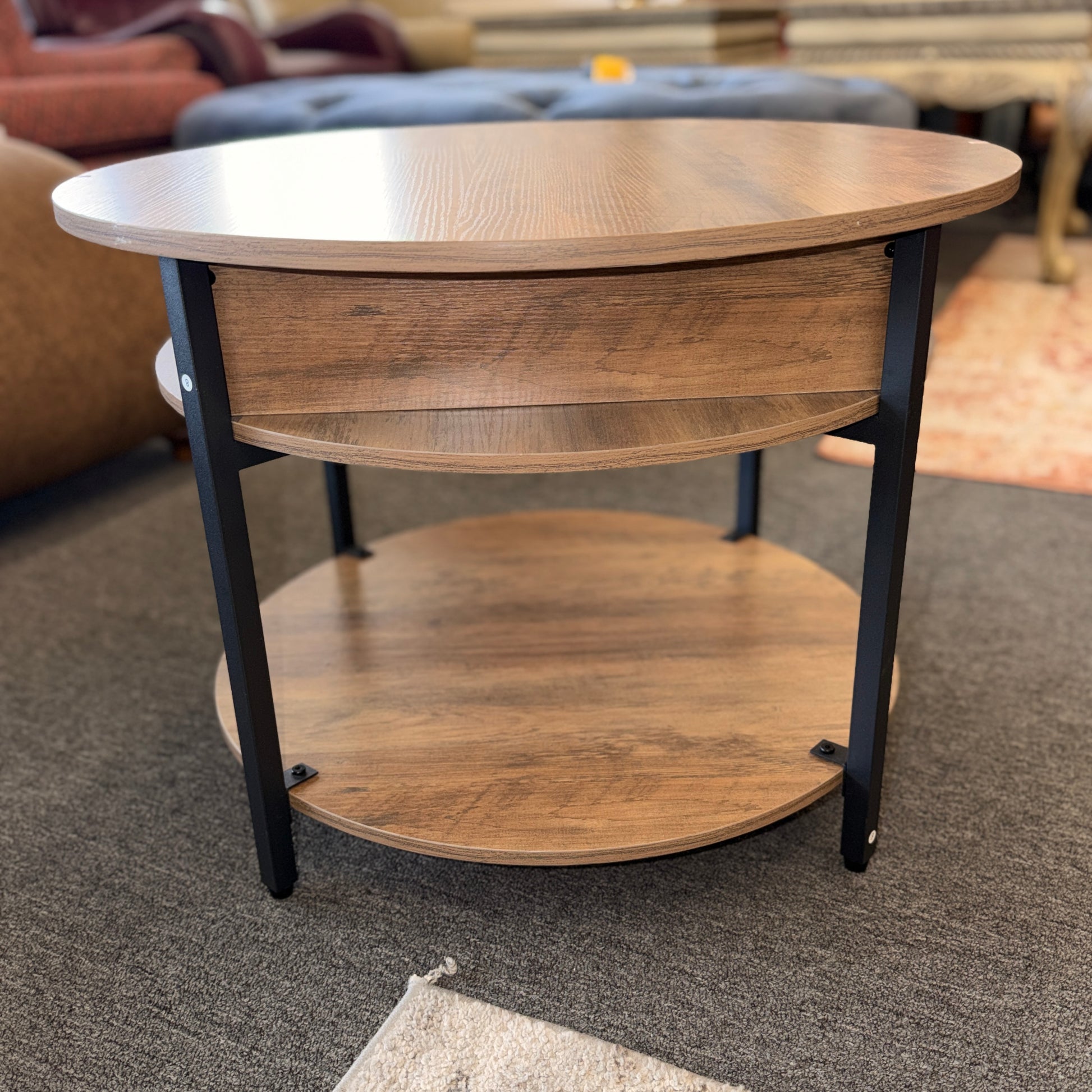 A round tiered wood-finish coffee table featuring a lift-top storage compartment in excellent condition.