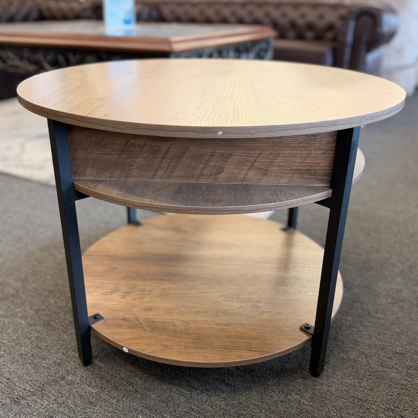 A round tiered wood-finish coffee table featuring a lift-top storage compartment in excellent condition.