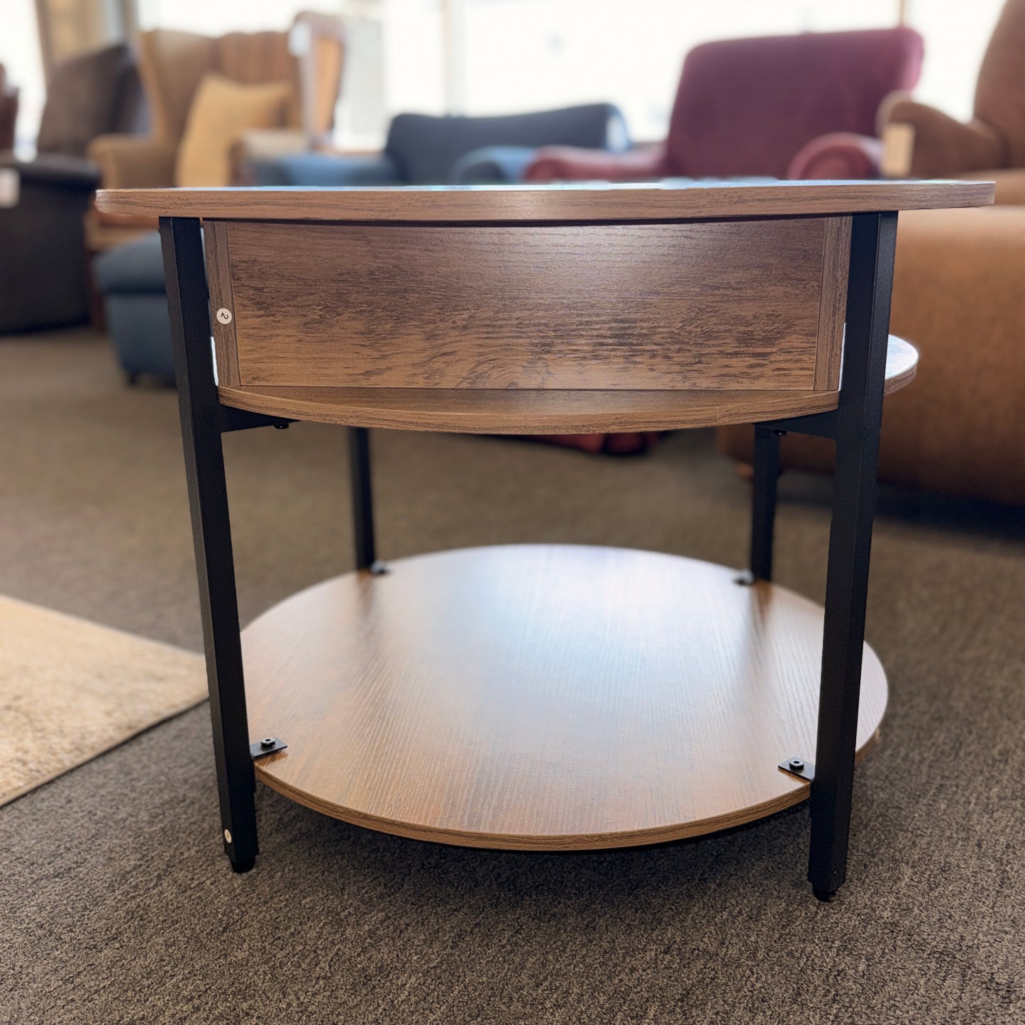 A round tiered wood-finish coffee table featuring a lift-top storage compartment in excellent condition.