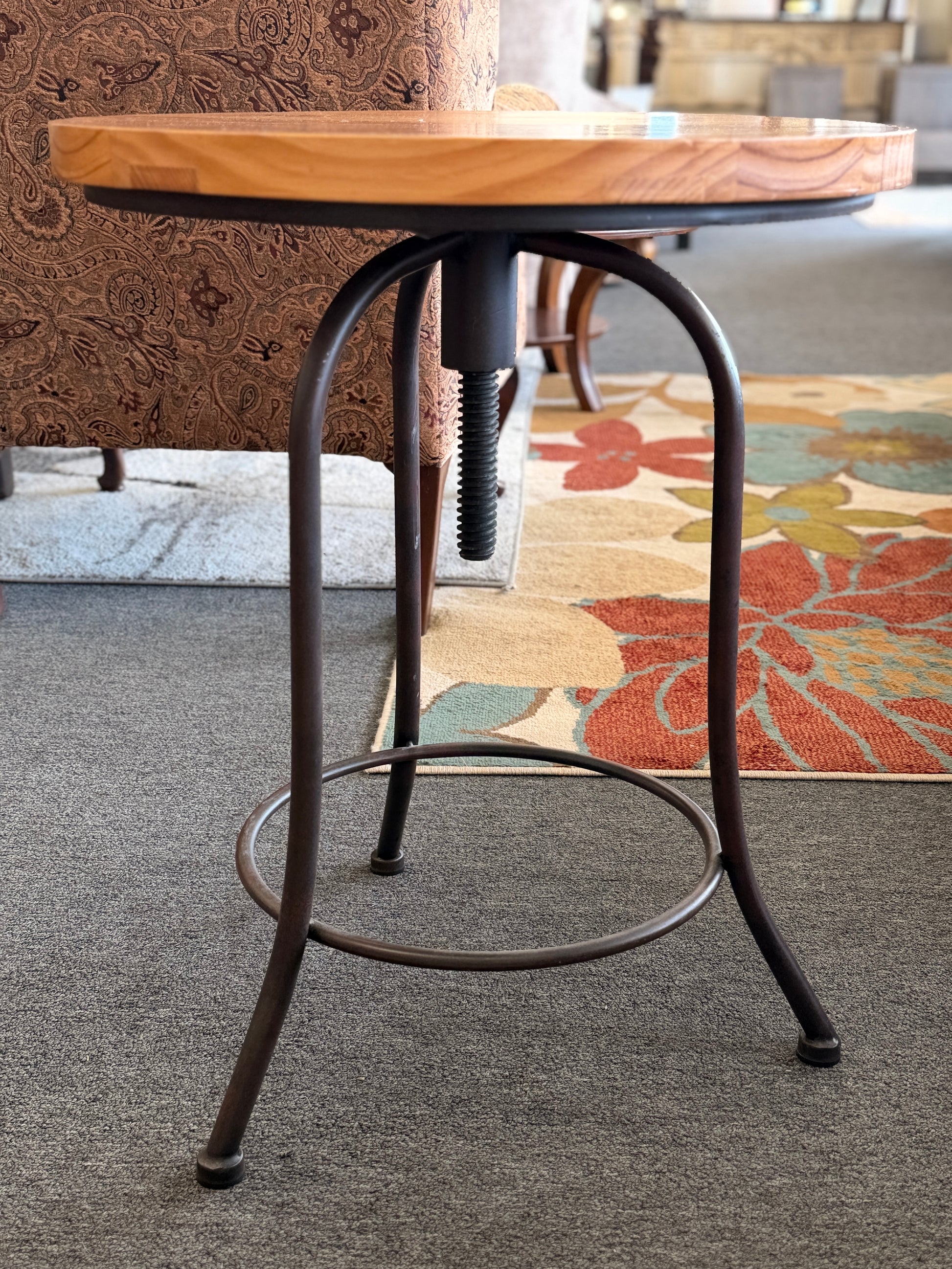 Round accent table featuring a natural wood plank-style top and a slender curved dark metal pedestal base with a lower support ring.