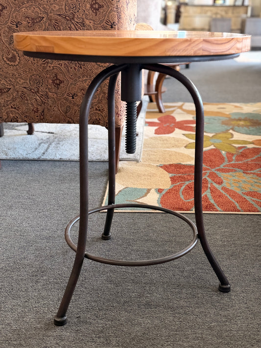 Round accent table featuring a natural wood plank-style top and a slender curved dark metal pedestal base with a lower support ring.
