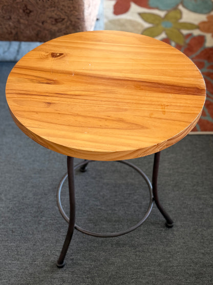 Round accent table featuring a natural wood plank-style top and a slender curved dark metal pedestal base with a lower support ring.