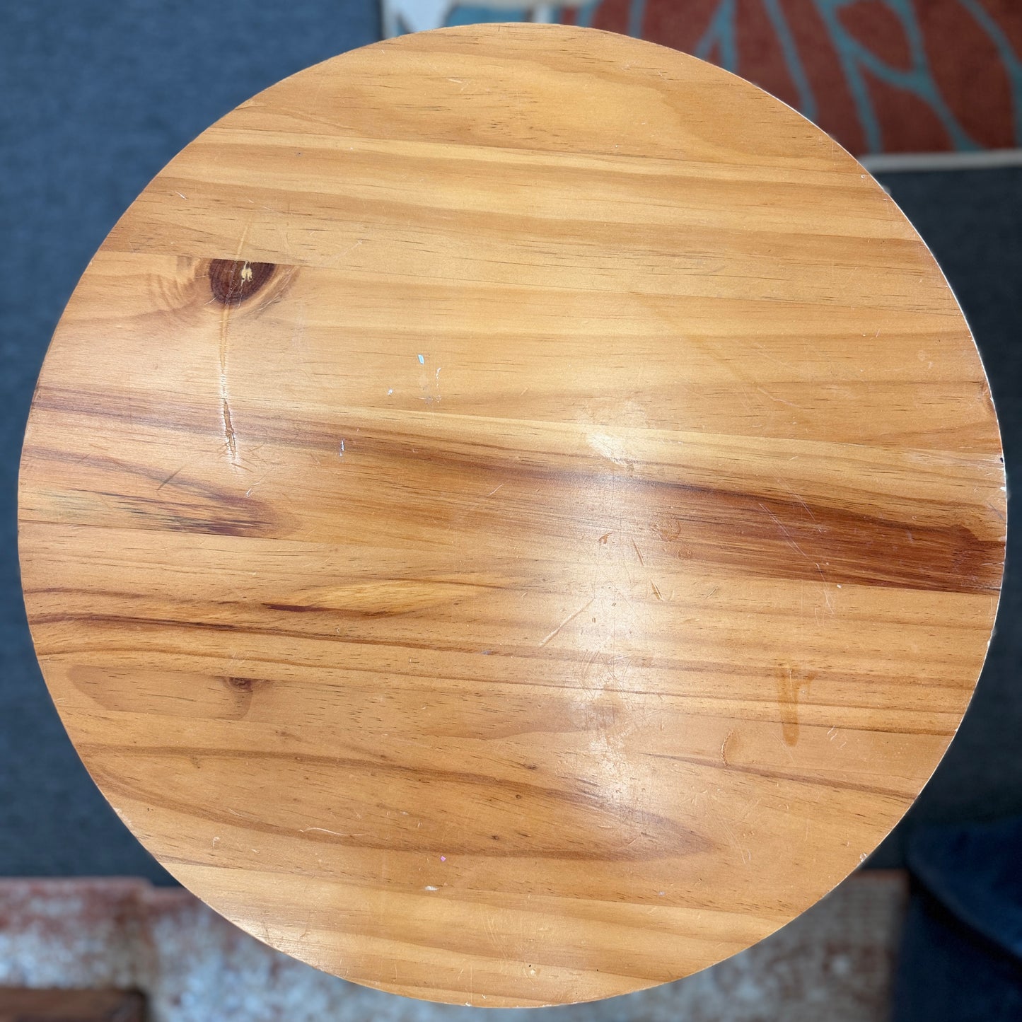 Round accent table featuring a natural wood plank-style top and a slender curved dark metal pedestal base with a lower support ring.