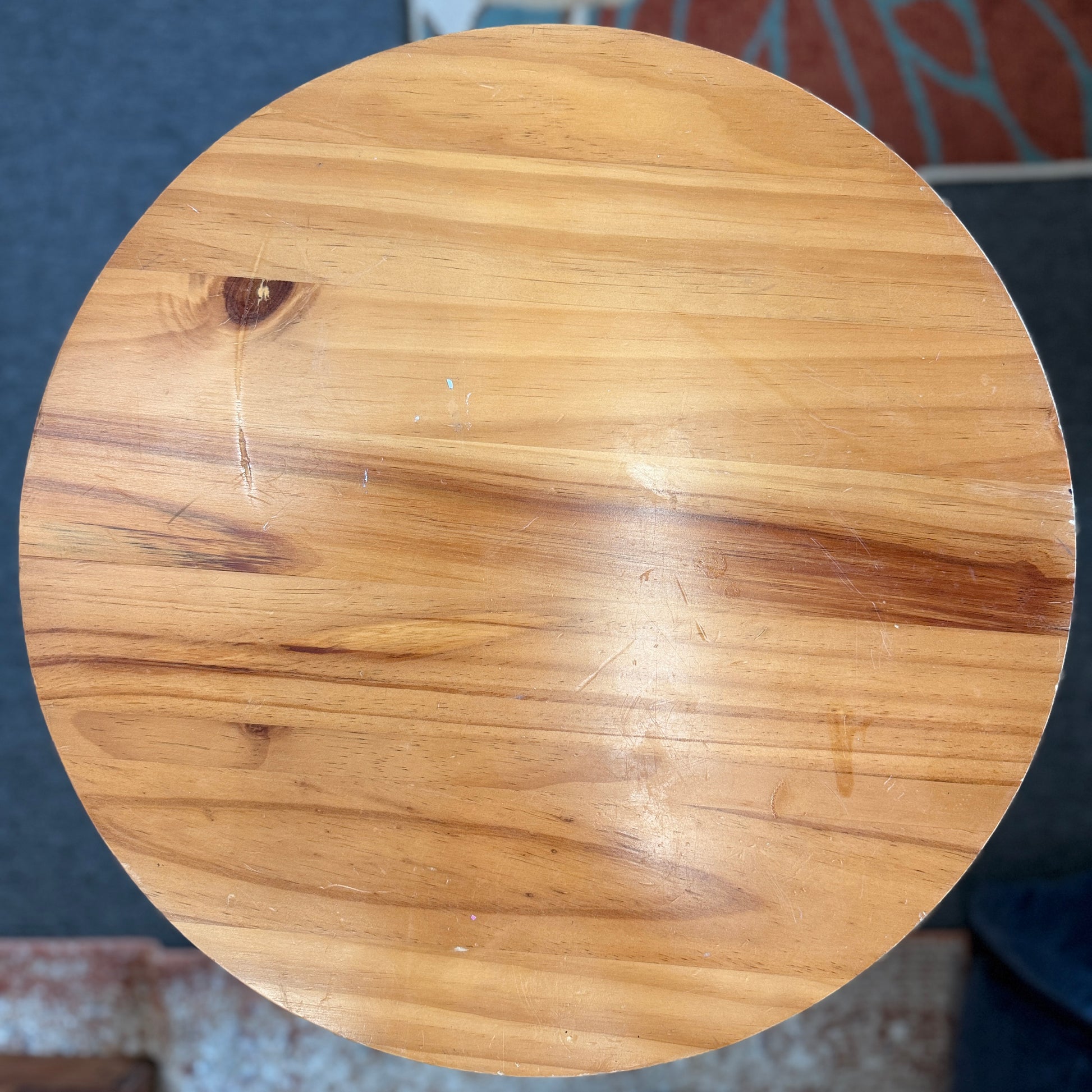 Round accent table featuring a natural wood plank-style top and a slender curved dark metal pedestal base with a lower support ring.