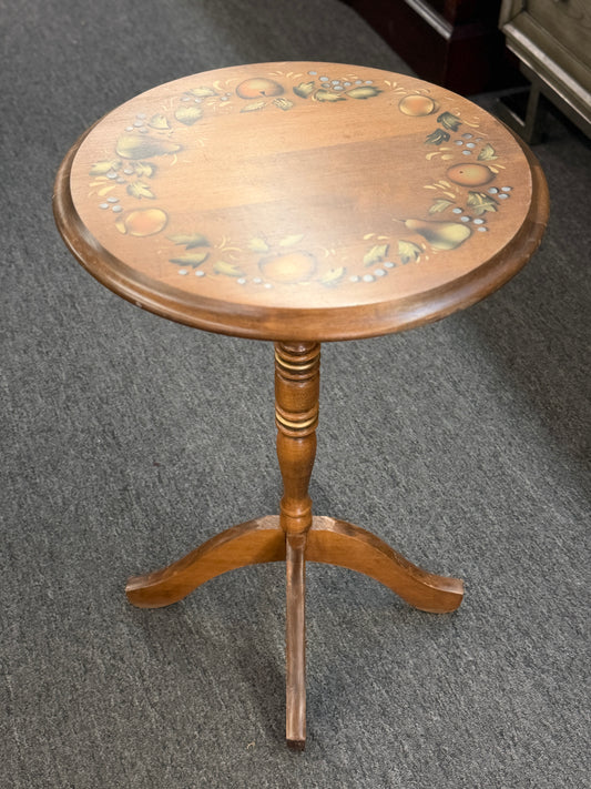 Round wooden pedestal accent table with a tripod base and a hand-painted rustic fruit and leaf border around the tabletop.