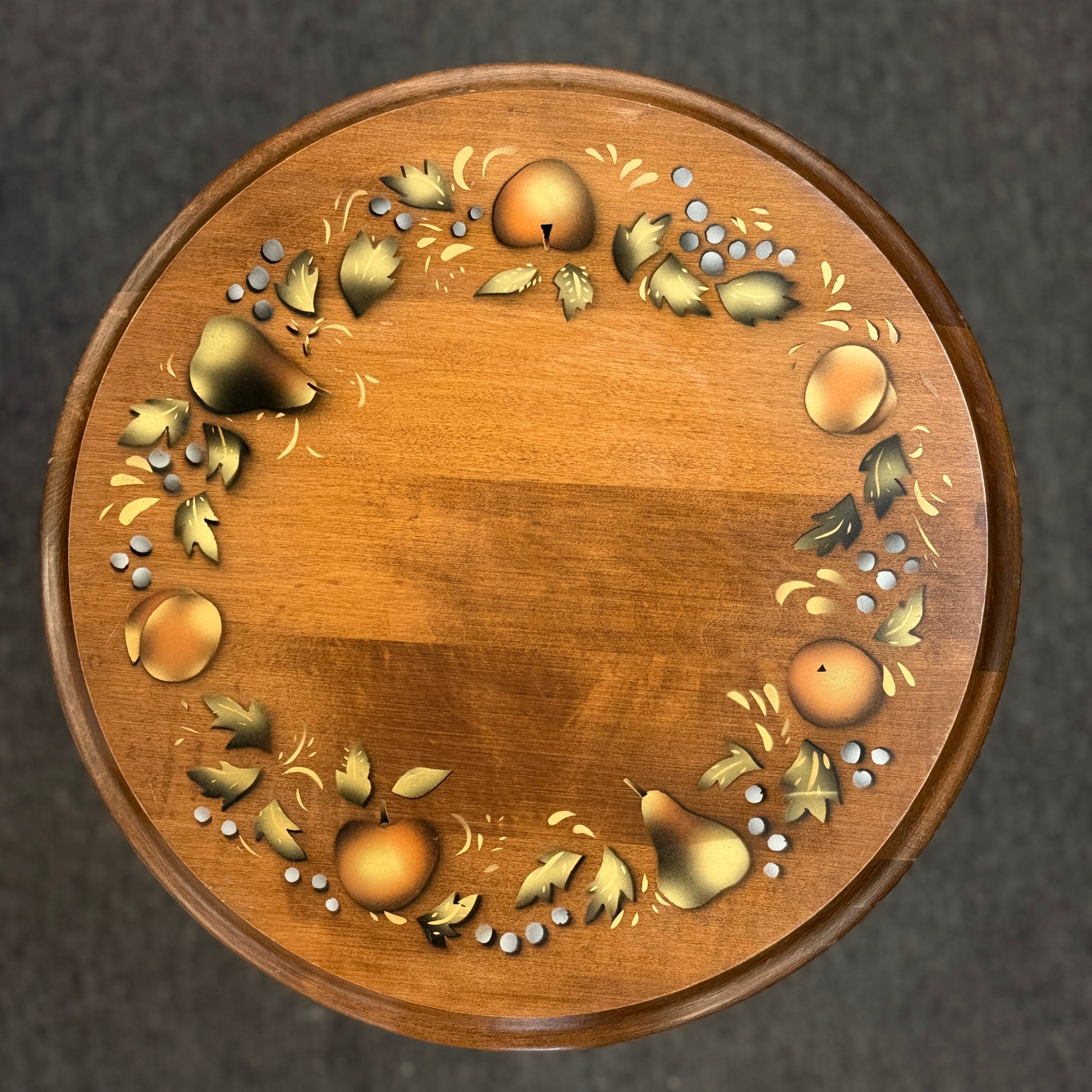 Round wooden pedestal accent table with a tripod base and a hand-painted rustic fruit and leaf border around the tabletop.