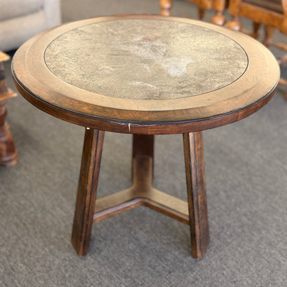 A round wooden side accent table featuring a rustic mottled stone or slate inlay top set over a sturdy pedestal-style base in good condition.