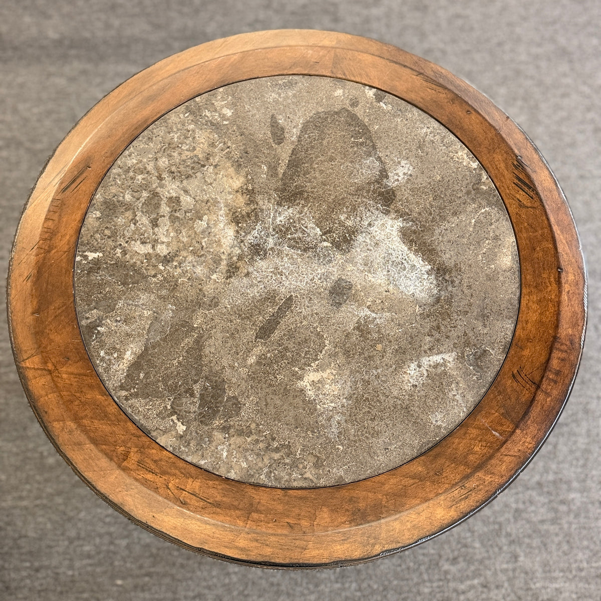 A round wooden side accent table featuring a rustic mottled stone or slate inlay top set over a sturdy pedestal-style base in good condition.