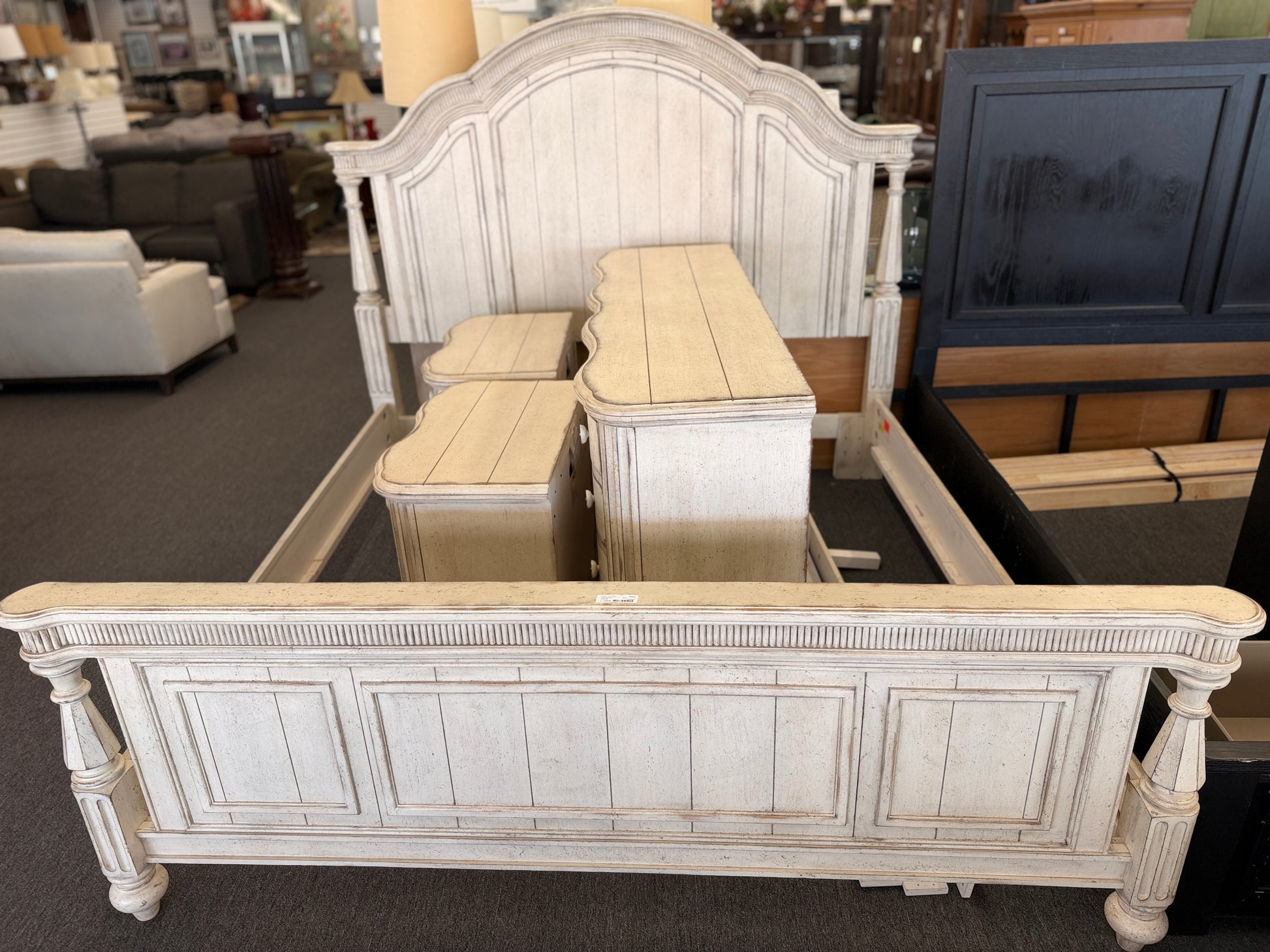 A 4-piece rustic cottage king bedroom set featuring an arched panel headboard bed frame, two nightstands, and a dresser in an antique whitewash finish.