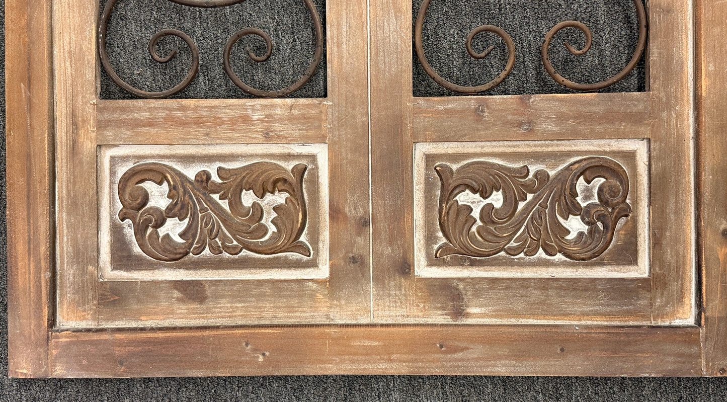 A large arched decorative wall panel designed like a rustic Tuscan door with a distressed wood frame and dark metal scrollwork gating.