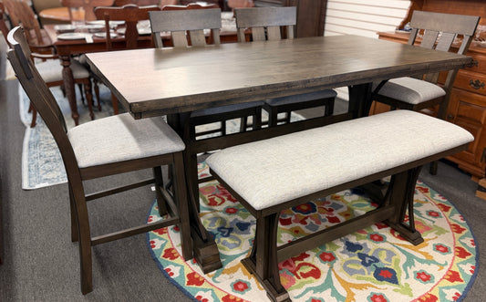 A rustic-modern counter-height dining set featuring a long wood and iron table, four matching slat-back chairs, and a long upholstered dining bench.