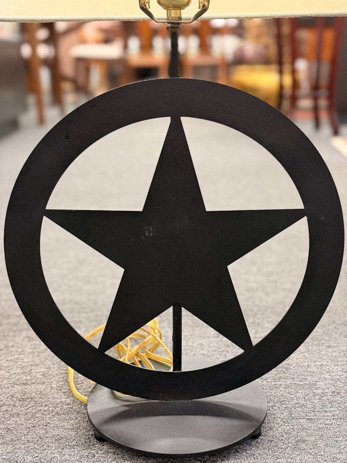 A rustic western-style table lamp featuring a black metal star-in-circle silhouette base topped with a rectangular off-white linen drum shade in good condition.